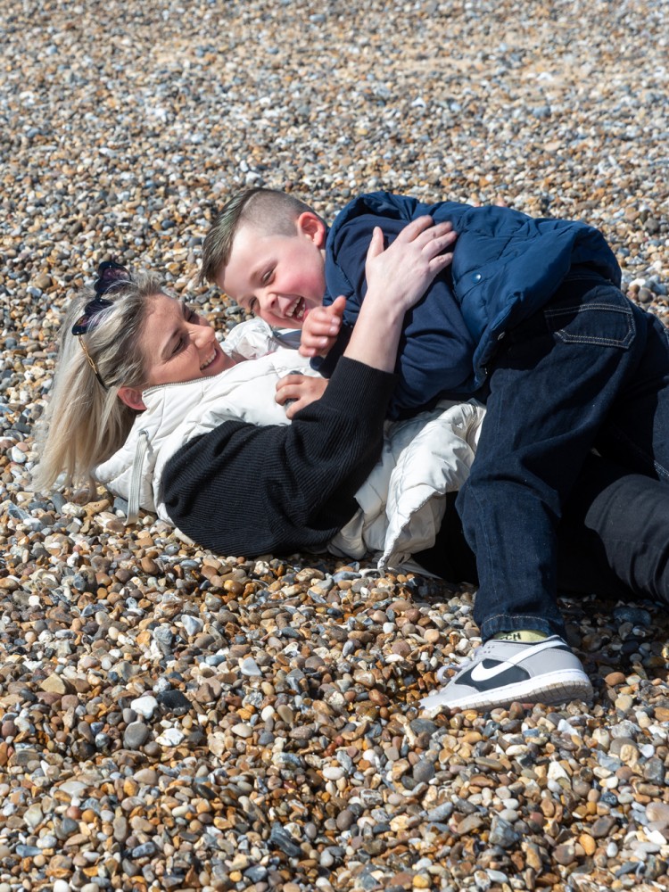 A mum and son laughing whilst playing on the beach in Gorleston